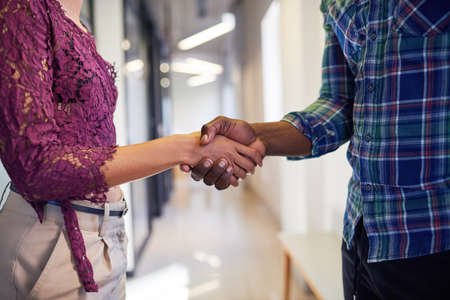 A close up of a handshake where a man and woman shake hands