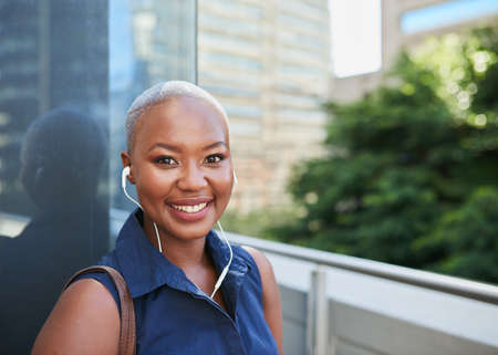 A young Black businesswoman arrives at the office with headphonesの写真素材