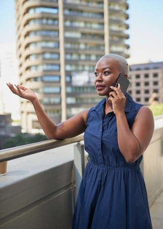 A Black businesswoman gestures on an important call on the city office balcony