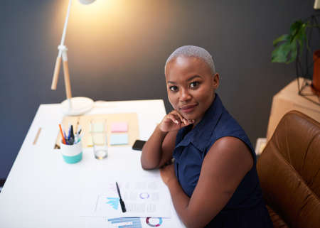 A young Black businesswoman sits at her desk late eveningの写真素材