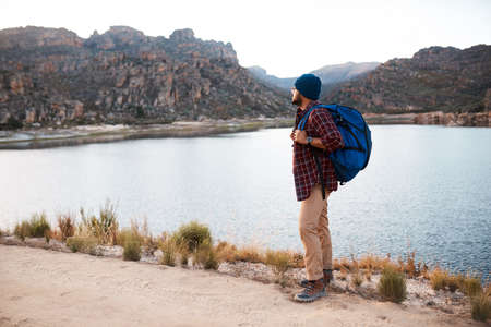 A backpacker takes a break at the lake while hiking in the mountains in eveningの写真素材