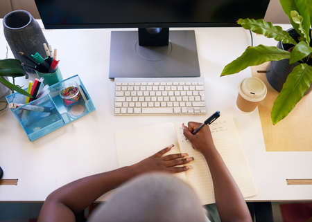 A young woman writes in her journal at a very neat desk staying organised