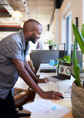 A Black businessman stands and leans over desk in the officeの写真素材