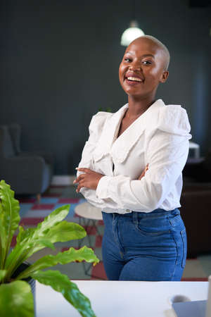 A confident young woman poses with arms crossed in her businessの写真素材