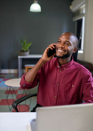 A Black man smiles while on a call in the creative office
