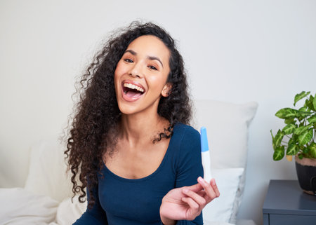 A young multi-ethnic woman is ecstatic and happy to see pregnancy test resultsの写真素材