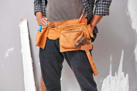 Close up cropped shot of a man wearing a tool belt with tools for home DIYの写真素材