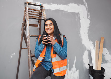 A young female construction worker takes a coffee break on site