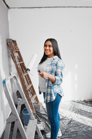 A young Indian woman prepares to paint a wall during home DIY projectの写真素材