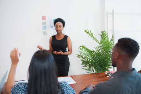 Business leader answers question from presentation attendee at meeting in officeの写真素材