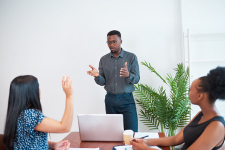 Business leader answers question from presentation attendee at meeting in office