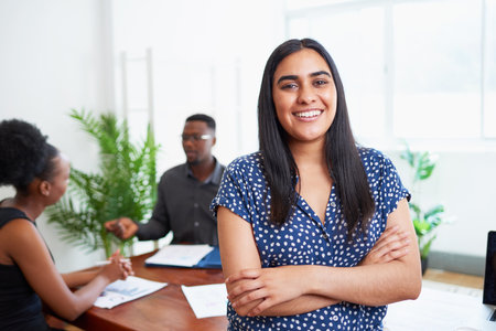 Portrait of smiling Indian business woman with diverse team in boardroom