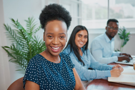 Portrait of young Black woman with natural hair, business meeting with coworkersの写真素材