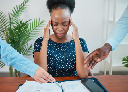 Young Black woman stressed at work due to paperwork and reportsの写真素材