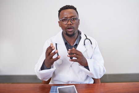 Serious Black doctor gestures with hands while discussing on telehealth call