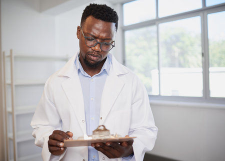 Portrait of a Black doctor holding clipboard with patient informationの写真素材