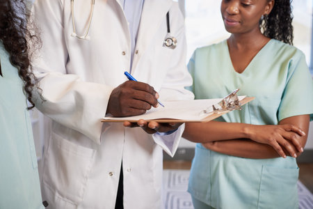 Cropped shot of doctor and nurses standing, writing on clipboard anonymousの写真素材