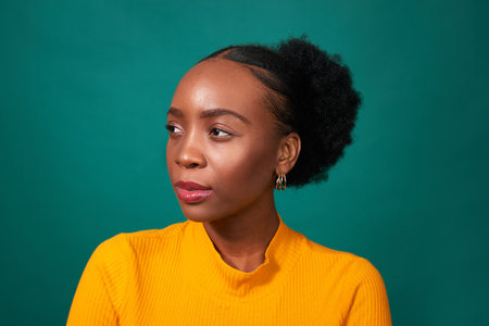 Beautiful Black woman smiles, studio teal background, fashion lifestyle portraitの写真素材