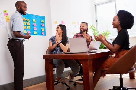 Team of developers clapping hands during sprint planning meeting in boardroomの写真素材