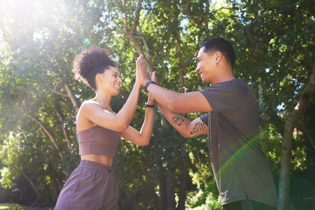 Beautiful fit couple give each other double high five after trail run outdoors