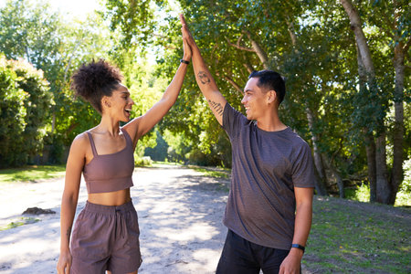 Beautiful young fit couple give high five after exercise in park, trail runの写真素材