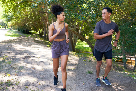 Fit couple runs together in park, trail running outdoors smiling and happyの写真素材