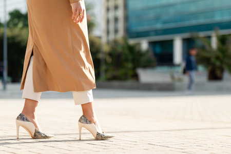Black Woman in Stylish Heels and Beige Coat Walking in Urban Business District