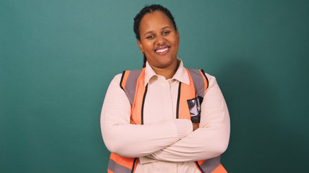 Young Black professional folds arms, dressed for work on construction site