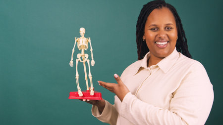 Young Black female doctor teaches human anatomy with model skeletonの写真素材