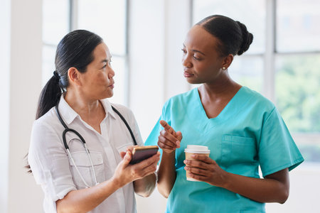 Diverse Female Doctors Consulting in Hospital Setting with Coffeeの写真素材