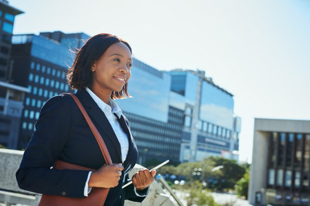 Confident Businesswoman in Urban Setting Carrying a Tablet and Bagの写真素材