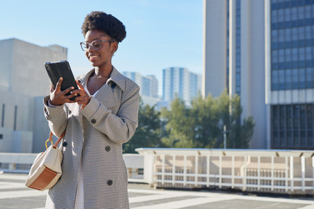 Smiling Woman Using Tablet in Urban Business Environmentの写真素材