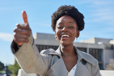 Confident Young Woman Giving Thumbs Up Outdoorsの写真素材