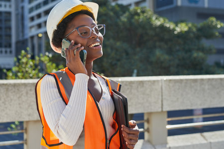 Confident Female Engineer Holding Phone and Tablet Outdoorsの写真素材