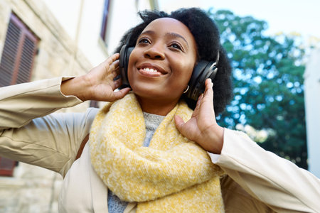 Joyful Woman Enjoying Music Outdoors in a Cozy City Setting with Wireless Headphonesの写真素材
