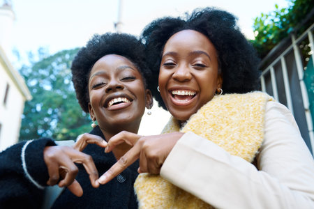 Joyful Friends Making Heart Shape with Hands in the City on a Bright Dayの写真素材