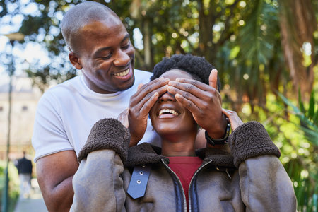 Joyful Couple Sharing a Playful Moment in an Urban Park with Nature and Happinessの写真素材