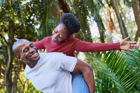 Joyful Couple Enjoying a Playful Moment Outdoors in a Lush Green Park Settingの写真素材