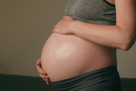 Expectant Mother Tenderly Holding Pregnant Belly in a Relaxed Setting, Highlighting Maternal Love and Connection and Beauty of Pregnancyの写真素材