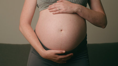 Close-Up of Pregnant Belly With Womans Hands Gently Cradling During Late Pregnancy in a Calm Settingの写真素材