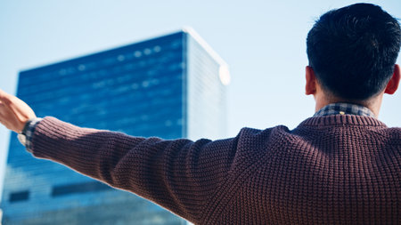 Asian Man Embracing Cityscape With Open Arms In Urban Environmentの写真素材