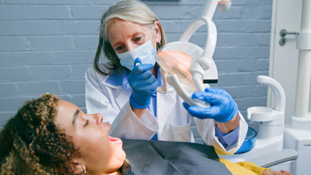 Professional Dentist Examining Patient with Modern Equipment in Clinicの写真素材