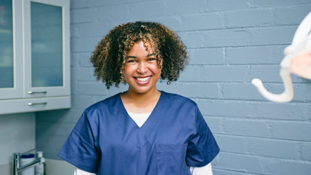 Smiling Female Healthcare Professional in Scrubs in a Dental Office Settingの写真素材