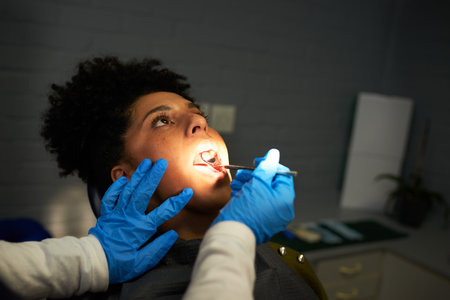 Patient Receiving a Dental Examination by a Professional Dentist Wearing Gloves in a Clinical Settingの写真素材