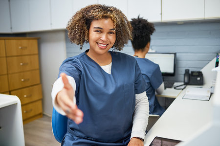 Friendly Healthcare Professional Reaching Out for a Handshake in a Medical Officeの写真素材