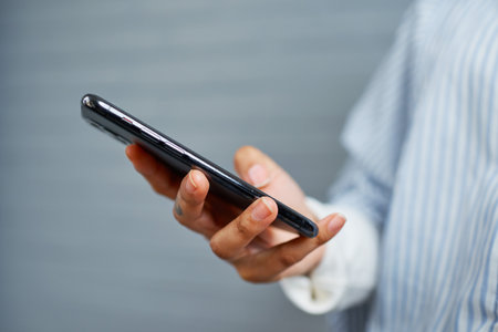 Person Holding Smartphone in Hand While Standing in Casual Outfit