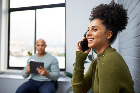 Professional Woman on Phone Call in Modern Office Setting with Male Colleague