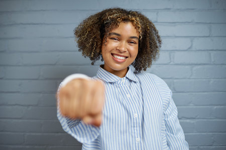 Confident Woman Displays a Proud Smile in Front of Brick Wallの写真素材