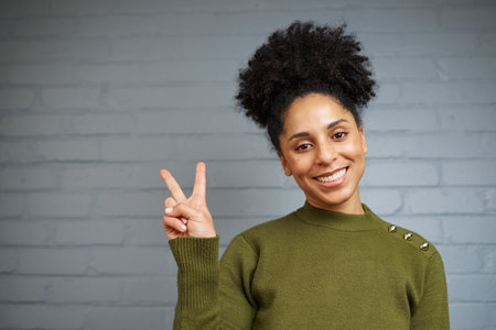 Cheerful Young Woman Making a Peace Sign With a Joyful Expressionの写真素材