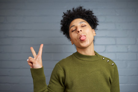 Woman in a Green Sweater Playfully Making a Peace Sign with a Fun Expression